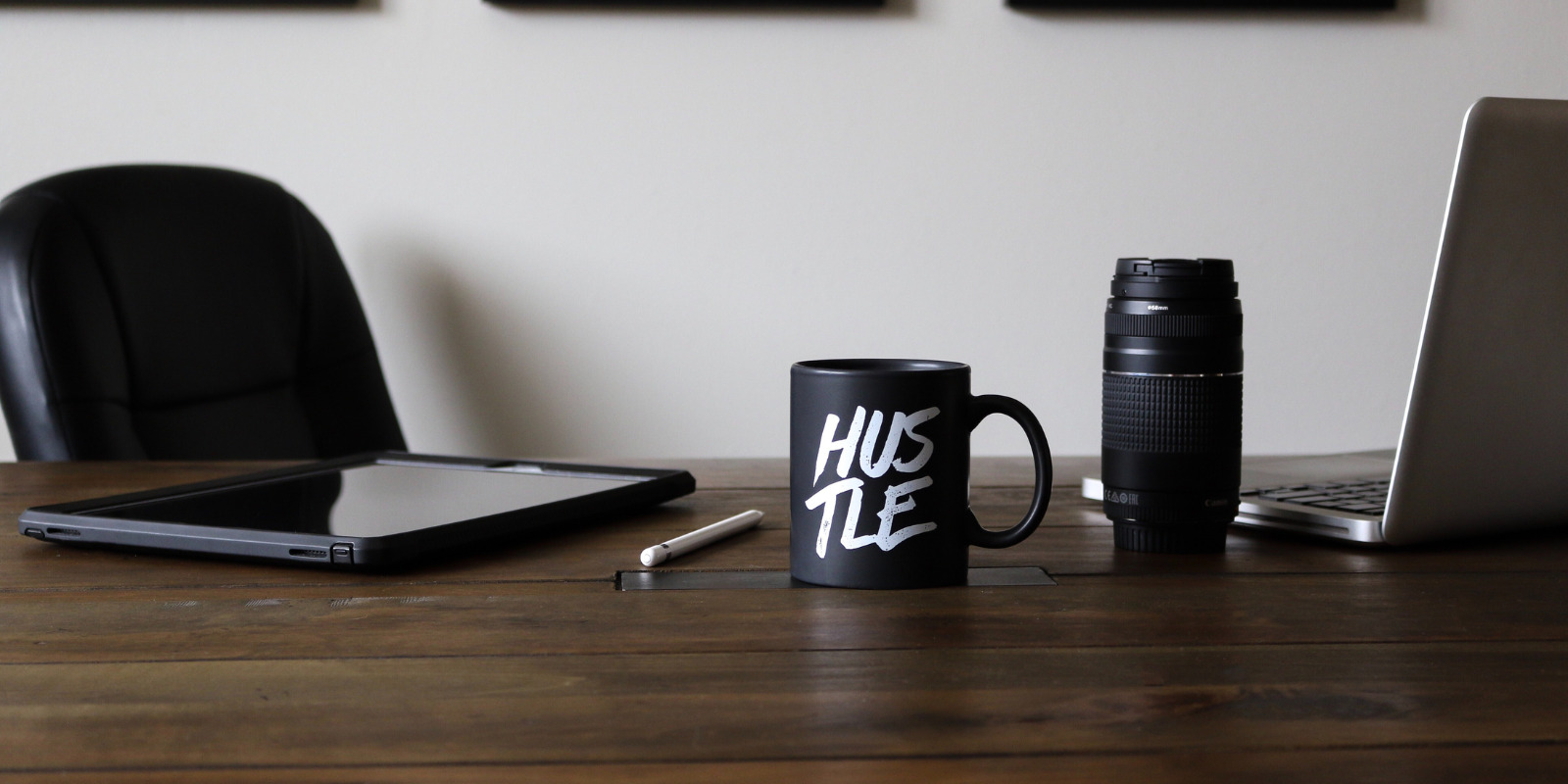 black coffee mug that says "hustle" on desk