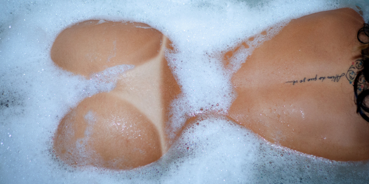 nude woman in bubble bath with summer tan lines