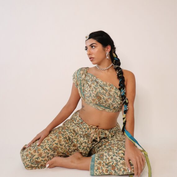Jasmine Sherni with black braided hair sitting on the floor wearing a traditional dress