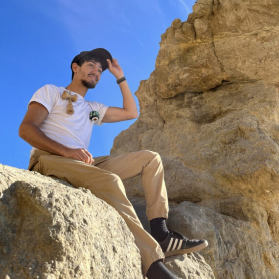 man sitting on a rock touching his cap