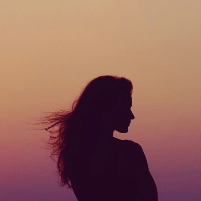 Woman's silhouette looking over her shoulder during a sunset