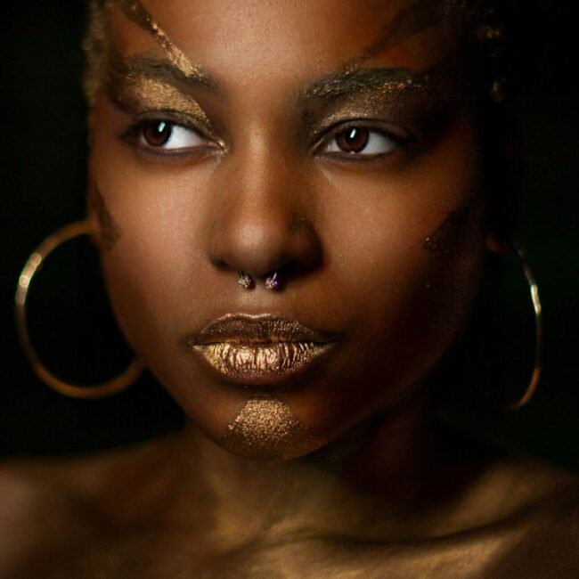 Black woman wearing gold face makeup