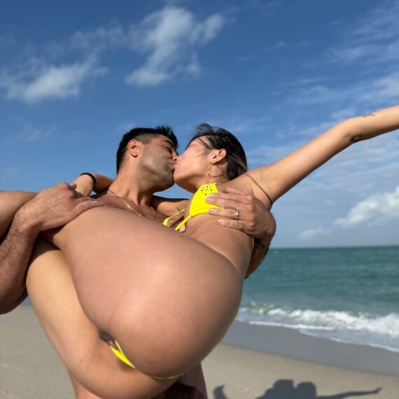 man lifting woman up at the beach and kissing