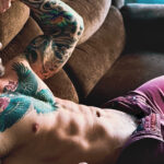 SHIRTLESS TATTOOES BALD MAN LAYING ON COUCH
