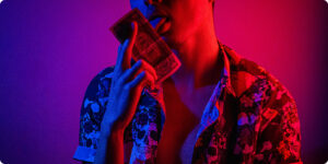man wearing a pattern shirt licking a dollar bill