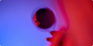 Woman with red lipstick looking at herself in a small mirror