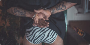 Man wearing zebra-printed underwear with cuffed hands