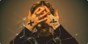 woman dressed in black with sticker shaped as crosses on her hand, cover in her face while tangled in lights