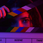 woman with hoodie on hiding behind a movie clipper