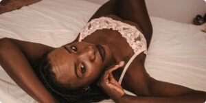Black woman laying in bed wearing pink flowered lingerie