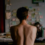 White man sitting on his desk from behind