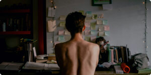 White man sitting on his desk from behind