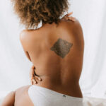 topless african american woman with a tattoo on her back
