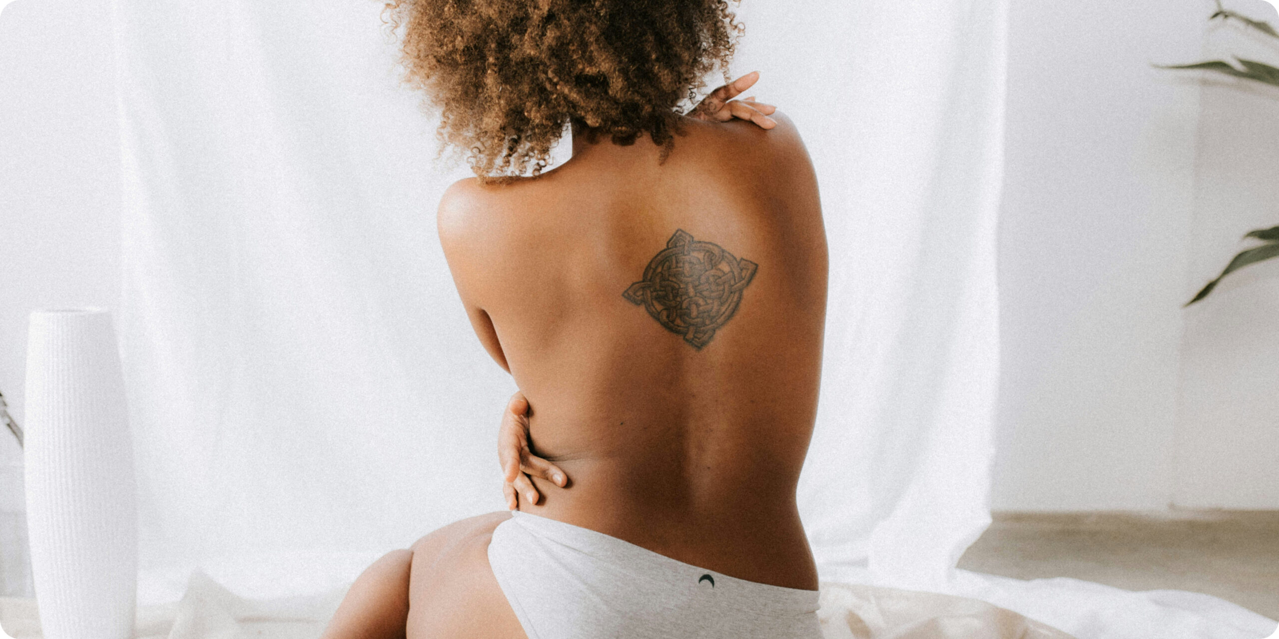 topless african american woman with a tattoo on her back